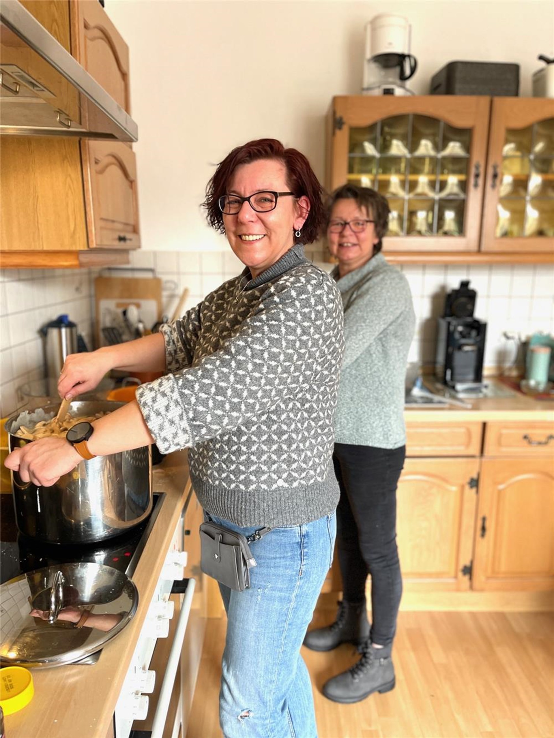 Zwei Sozialarbeierinnen kochen für 30 Personen und rühren in einem großen Topf