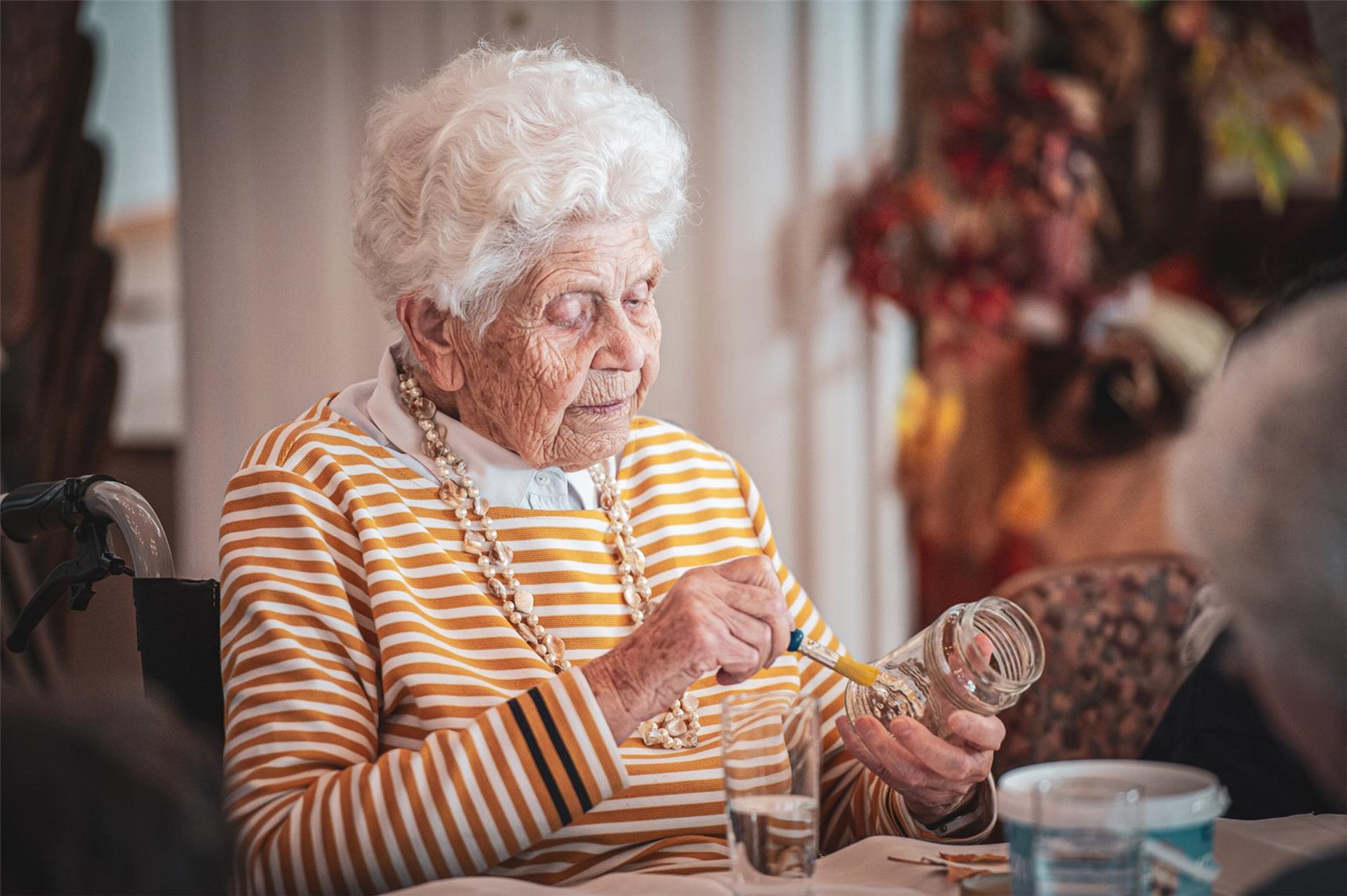 Alte Dame gestaltet Windlicht mit Laub