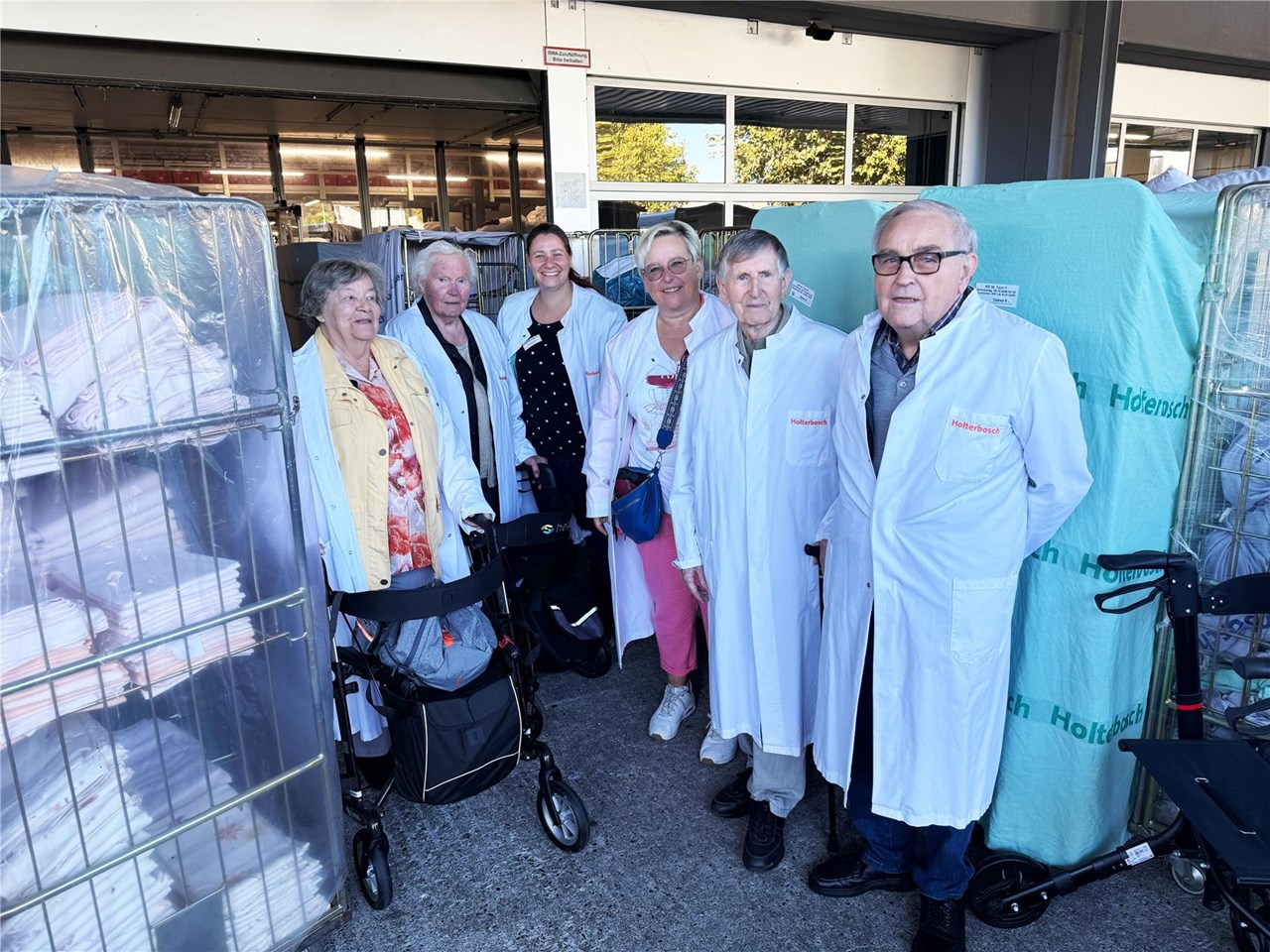 Bewohner unserer Alteneinrichtungen beim Besuch der Wäscherei Holterbosch in Krefeld vor großen Wäschewagen